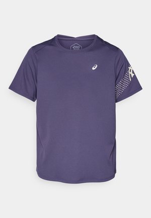 Camiseta deportiva morada de manga corta, con tejido texturizado, escote redondeado y un logo en el pecho. Patrón de lunares en la manga.