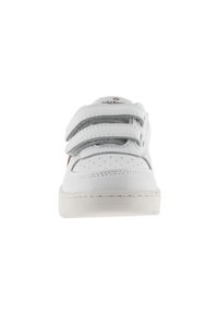 Sneaker bianco con punta perforata, tre strap regolabili in velcro e suola beige. Presenta un logo sulla linguetta e accenti grigi a contrasto.