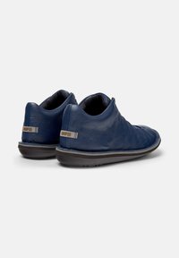 Marineblauwe leren schoenen met een zachte uitstraling, voorzien van een lichte hak en een gestructureerd oppervlak. Het merkembleem is zichtbaar op de hiel.