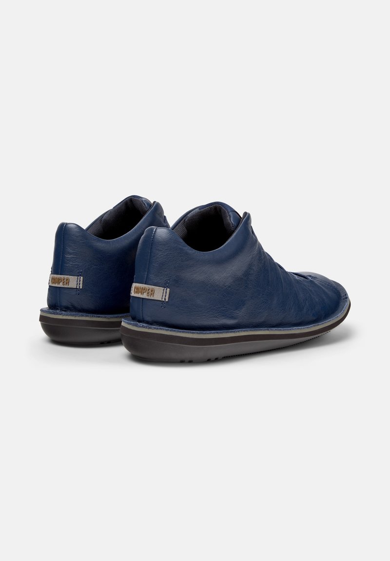 Marineblauwe leren schoenen met een zachte uitstraling, voorzien van een lichte hak en een gestructureerd oppervlak. Het merkembleem is zichtbaar op de hiel.