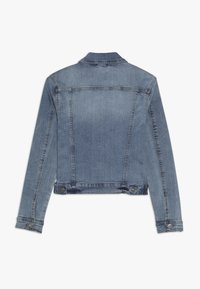 Modrá denimová bunda s kratším střihem, se špičatým límcem, dvěma předními knoflíky a viditelnými švy na zadní straně a rukávech.