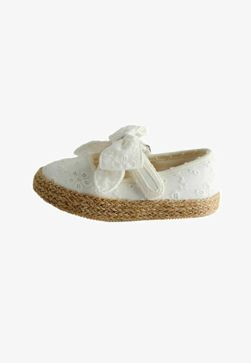 Zapato blanco para niño pequeño con bordado floral, gran lazo de tela en la correa y suela de yute tejida, mostrado de lado sobre un fondo blanco.