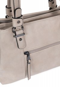 Beige handtas met een gestructureerd oppervlak, voorzien van een ritsvak aan de voorkant, verstelbare hengsels en metallic hardware-accenten. Merkenlogo zichtbaar.