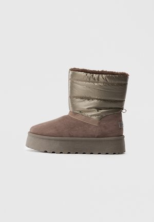 Botte d'hiver mi-haute avec une partie inférieure en suède marron, une partie supérieure en métal rembourré, une semelle en caoutchouc épaisse et une douce doublure en fourrure visible en haut.
