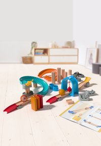 Wooden toy construction set featuring colorful tracks in teal, orange, and red, with various shapes and a playful design. Instruction manual included.