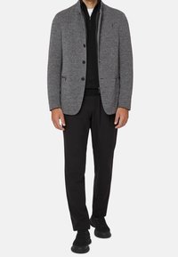 Gray blazer with a textured fabric, black zip-up underlayer, black trousers, and black sneakers. Features buttons and side pockets.