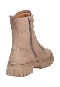 Bottine beige avec une finition en suède texturé, fermeture éclair sur le côté et un design à lacets. Caractérisée par une semelle en caoutchouc épaisse avec un motif de sculpture prononcé.