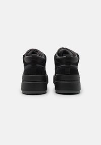 Czarne wysokie trampki wykonane z zamszu i materiału syntetycznego, z teksturowanym wnętrzem oraz grubą czarną gumową podeszwą. Posiadają podwójne uchwyty na pięcie.