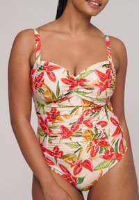 Bañador de una pieza floral en color beige claro, con vibrantes patrones en rojo y verde, laterales fruncidos y tirantes ajustables para mayor comodidad.