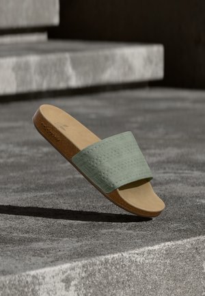 Παντόφλα τύπου σλάιντ με επάνω μέρος σε μέντα πράσινο με υφή και ταμπά πάτο. Ο σχεδιασμός διαθέτει σολάκι από φελλό και μινιμαλιστική σιλουέτα.
