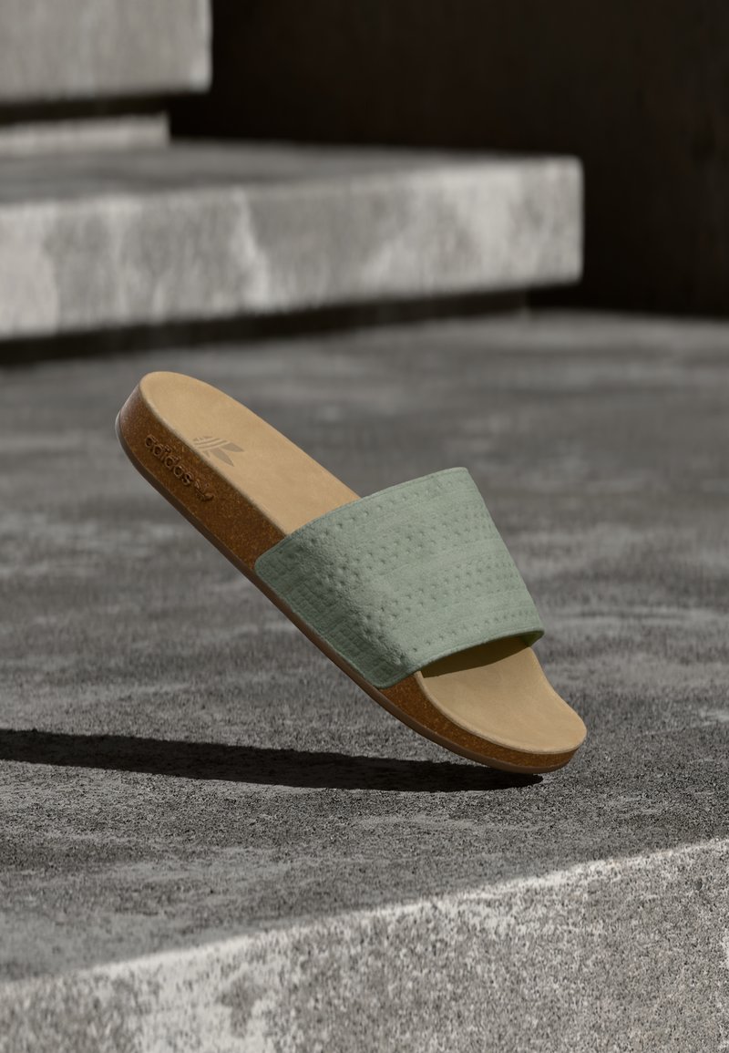 Παντόφλα τύπου σλάιντ με επάνω μέρος σε μέντα πράσινο με υφή και ταμπά πάτο. Ο σχεδιασμός διαθέτει σολάκι από φελλό και μινιμαλιστική σιλουέτα.