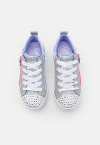 Baskets argentées pailletées avec des lacets blancs, ornées de motifs colorés, d'accents roses et de clous argentés à la pointe. Zip latéral inclus.