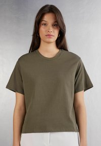 Olivgrön bomulls t-shirt med korta ärmar, rund halsringning och avslappnad passform. Slät textur, inga synliga mönster eller detaljer.