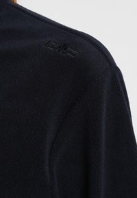 Mörk marinblå fleece-tröja med en broderad logotyp på axeln, som visar en jämn textur och minimalistisk design.