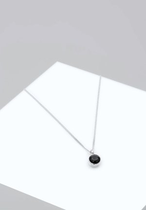 Collier en chaîne argentée avec un pendentif rond en pierre noire facettée, monté dans une monture en argent poli.
