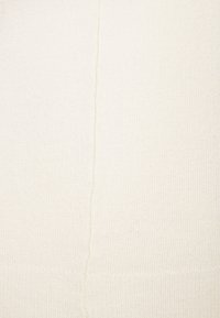 Tessuto a maglia crema con una superficie a costine e dettagli di cucitura verticale. La superficie appare morbida e spessa, adatta per calore e comfort.