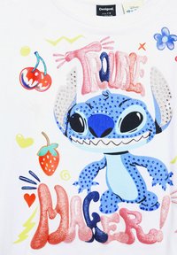 Camiseta blanca con un personaje de dibujos animados azul, con ojos grandes y dientes afilados. Texto colorido "¡CREADOR DE PROBLEMAS!" con acentos brillantes y gráficos juguetones.