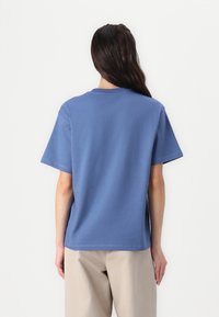 Blaues Baumwoll-T-Shirt mit kurzen Ärmeln, lockerer Passform, minimalen Nähten und Rundhalsausschnitt, von hinten betrachtet.