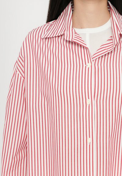 Rdeče in bele črtaste srajce s konico ovratnikom, ki ima zaponko na gumb in lahkotno tkanino. Gladka tekstura z navpičnimi črtami.