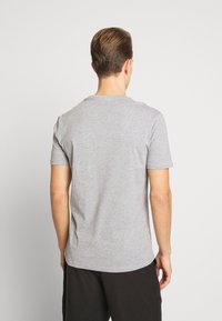 Camiseta de algodón gris con mangas cortas, cuello redondeado y un corte relajado. La tela tiene una textura suave y un diseño minimalista.