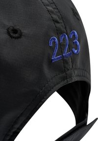 Svart keps med blå broderade siffror "223" på sidan, tillverkad av ett slätt, texturerat tyg och med ett justerbart band bak.