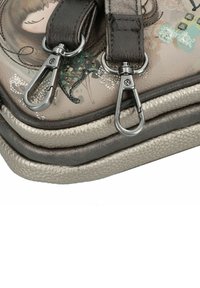 Multifarbige Handtasche mit einer strukturierten Lederoberfläche, zwei verstellbaren Riemen und Metallclips. Das Design umfasst florale Muster und Verzierungen.