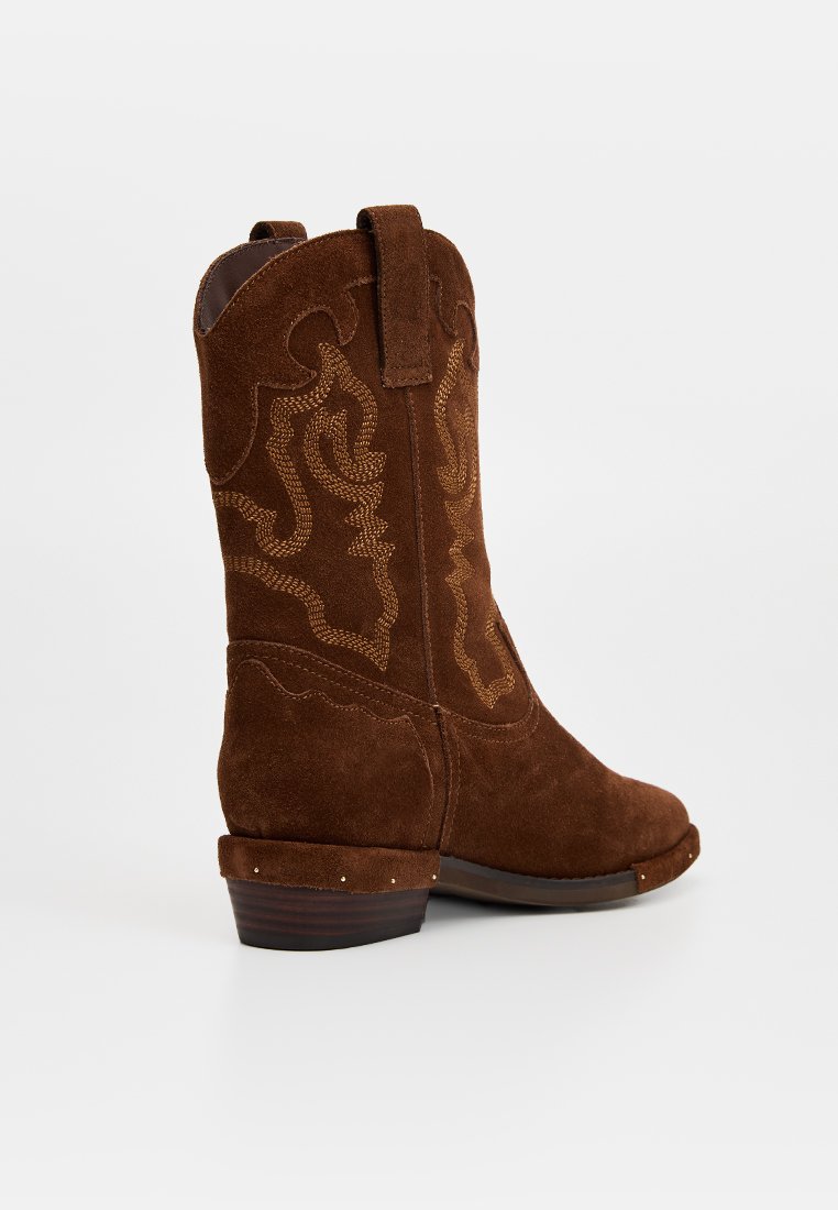 Braune Wildleder-Cowboystiefel mit kunstvoller goldener Stickerei, einem moderaten Absatz und dekorativen Akzenten am oberen Rand und an der Zehenpartie.