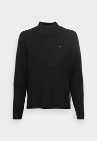 Zwarte geribbelde trui met een hoge, opgerolde halslijn, voorzien van raglanmouwen en een klein logo op de borst. Gestructureerde stof voegt detail toe.