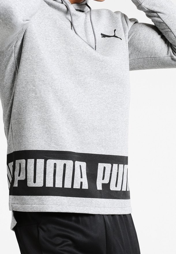 Grå hoodie av mjukt material. Har en svart logotyp på bröstet och ett djärvt svart band med "PUMA" i vitt vid fållen.