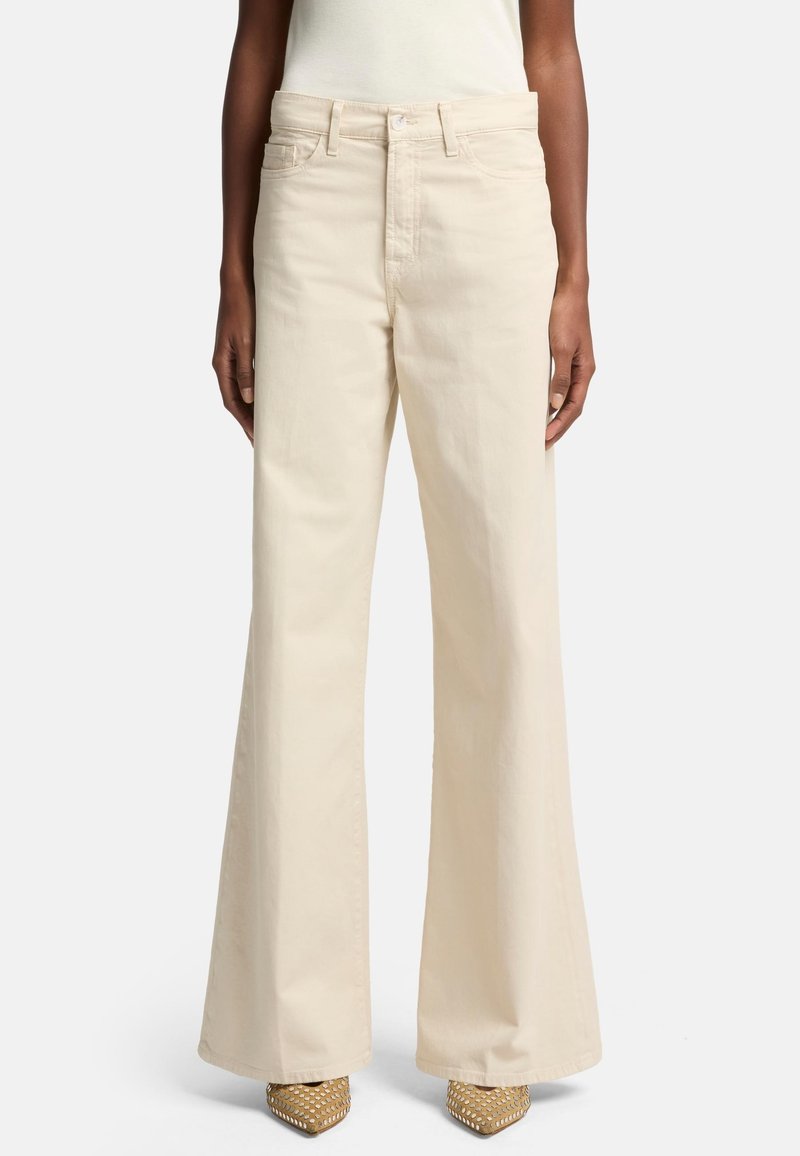 Pantalons larges beige en coton, dotés de poches avant, d'une taille haute et d'une texture lisse, assortis à des talons beige ornés.