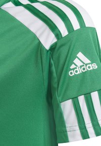 Maglia sportiva verde con dettagli bianchi e tre strisce bianche sulla spalla. Include il logo Adidas sulla manica.
