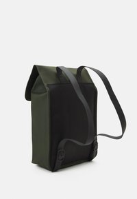 Sac à dos vert et noir de forme rectangulaire, comportant un rabat supérieur, des bretelles noires ajustables et des coutures renforcées.