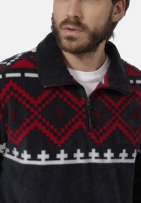 Fleece-Pullover in dunkelblau mit roten und weißen geometrischen Mustern, Viertelreißverschluss-Halskragen und strukturiertem Stoff.
