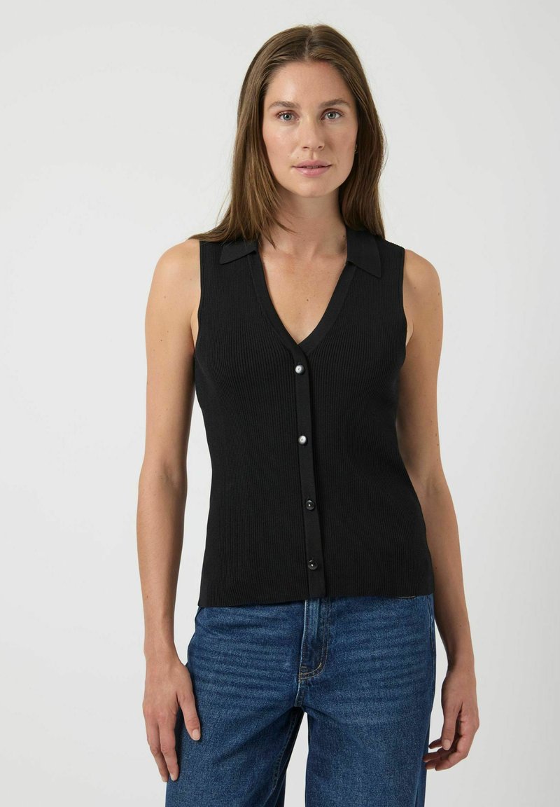 Top sin mangas negro de canalé con escote en V, cierre de botones y detalles en el cuello, combinado con jeans azules. Textura suave y diseño ajustado.