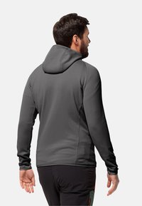 Grijs hoodie sweatshirt met lange mouwen, een gladde textuur en een slim fit ontwerp, bekeken vanaf de achterkant, gecombineerd met zwarte broek.