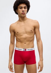 Κόκκινα βαμβακερά boxer briefs με λευκή ελαστική ζώνη μέσης που φέρει το λογότυπο "TOMMY HILFIGER" και μια μικρή λεπτομέρεια λογότυπου στο κέντρο.