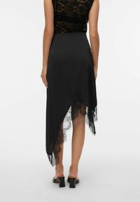 Melnas asimetriskas kleita ar mežģīņu apakšu, gludu audumu, bez piedurknēm un plūstošu siluetu.