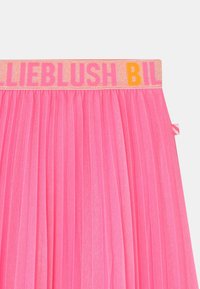 Lyserød plisseret nederdel med en glitrende talje, hvor der står "LIEBLUSH BIL" med lyse bogstaver. Blødt, tekstureret materiale med levende farve.