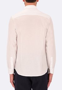 Camicia bianca a maniche lunghe con una texture liscia, colletto classico e polsini abbottonati, con orlo curvo e dettagli sulla spalla posteriore.