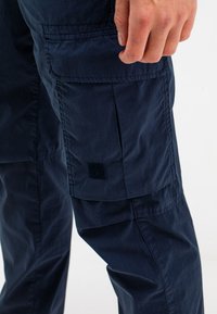 Marine cargobroek van lichtgewicht stof met een grote zijzak en een klein logo-opdruk, met een gladde textuur en een getailleerde pasvorm.