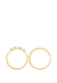 Anillos de oro con acentos de ópalo iridiscente; uno presenta tres piedras grandes en fila, mientras que el otro tiene piedras más pequeñas espaciadas uniformemente.