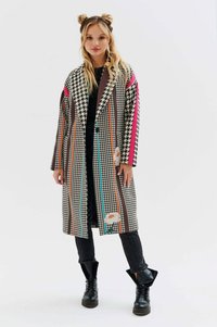 Wzorzysta długa kurtka z motywem houndstooth, wielokolorowymi paskami, akcentami kwiatowymi i luźnym krojem. Posiada duże klapy i boczne kieszenie.