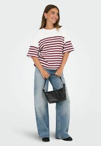 Gestreept T-shirt in wit en bordeaux, ontspannen pasvorm. Gecombineerd met lichtblauwe, wijde jeans en een zwarte tas met zilveren hardware-accenten.