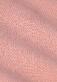 Tissu rose clair avec une texture lisse, présentant un motif à mailles serrées et de subtiles variations de teinte. Idéal pour les vêtements ou les accessoires.