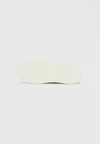 Beli podplat superge z teksturiranim vzorcem diamantnih oblik in žlebov za oprijem, z gladkim robom in čistim dizajnom.