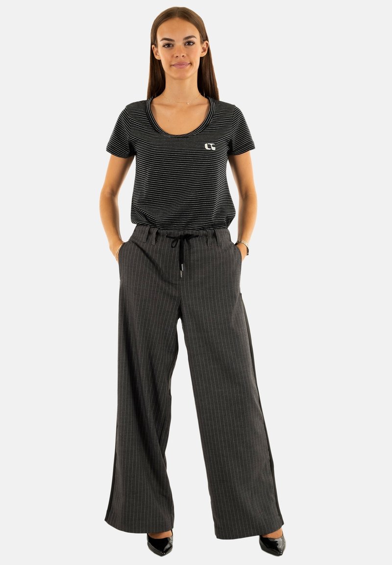 T-shirt à rayures noires et blanches avec un encolure ronde, associé à un pantalon large à rayures grises avec une taille ajustable.