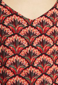 Tecido com padrão vermelho e preto apresentando um design floral com detalhes em verde; a textura é suave com um motivo vibrante e intrincado que se repete.