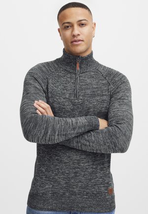 Quarter-zip textured sweater in dark gray and light gray tones, featuring ribbed cuffs and a leather logo patch on the hem.