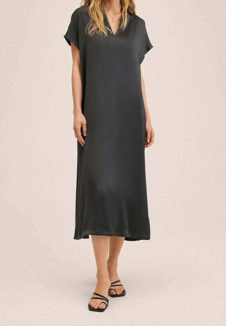 Robe noire, coupe A-line, longueur genou, avec des manches dolman courtes, encolure en V, et tissu lisse. Assortie à des sandales plates noires, au design minimal.