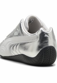 Baskets argentées avec une finition métallique lisse, une semelle en caoutchouc grise texturée et des détails blancs subtils. Bout arrondi et col rembourré.